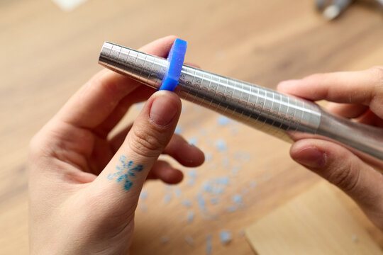 Close up of young adult female jeweler measuring blue ring on mandrel, practicing jewelry sizing and craft skills. Useful for handmade business, artisan workshop, product education marketing