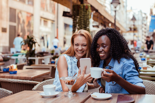 Two women looking at smartphone at outdoor cafe
