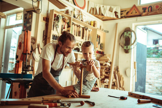 Father teaching daughter woodworking in home workshop