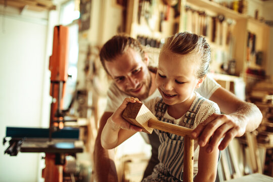Father teaching daughter woodworking in home workshop