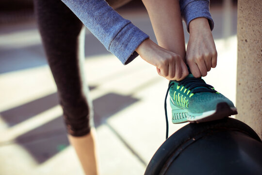 Runner tying shoelaces on green sneaker outdoors