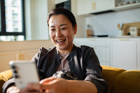 Smiling woman making video call on smartphone at home