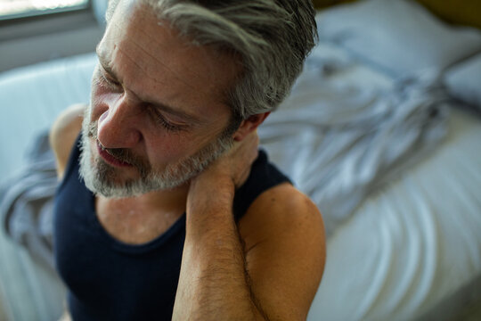 Mature man with neck pain in home bedroom