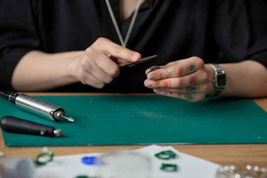 Close up of young adult woman shaping ring with hand file at workbench, creating handmade jewelry for small business production. Ideal for artisan branding, craft commerce, retail marketing