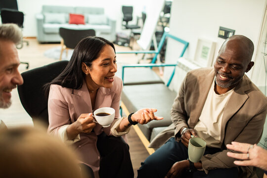 Coworkers having coffee chat in office lounge