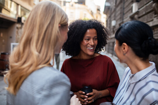 Smiling women networking with coffee on a city street