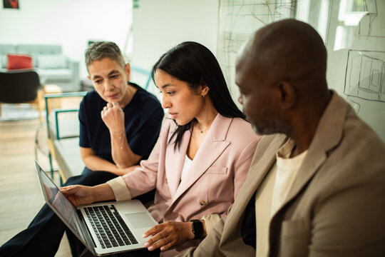 Diverse colleagues collaborating on laptop in modern office