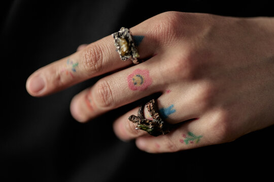 Close up of child hand displaying handmade foil and twig rings with colorful stamp marks, suggesting creative play and craft activity. Useful for childhood creativity or DIY education campaigns