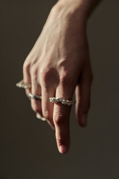 Vertical shot of young adult womans hand pointing downward while wearing textured rings, suggesting jewelry styling and product focus. Ideal for accessory branding, fashion retail