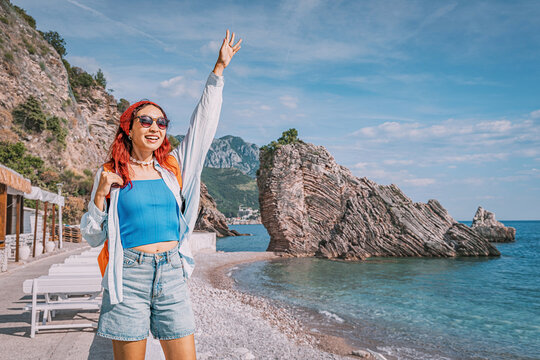 Happy young woman traveler enjoying summer vacation on Budva seaside, admiring the beautiful view of Adriatic coast