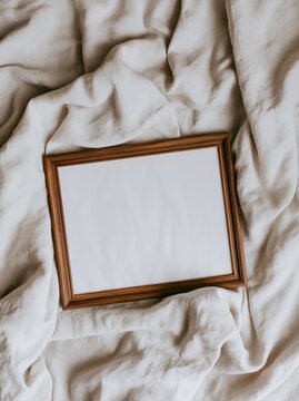 blank frame lies on wrinkled piece of fabric in light setting. surface shows soft textures blending with frames natural color