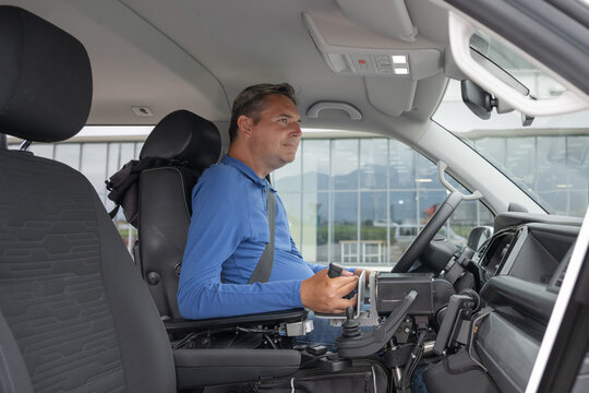 Wheelchair user operating a vehicle adapted for independent driving in everyday travel. Disability and inclusive mobility concept.