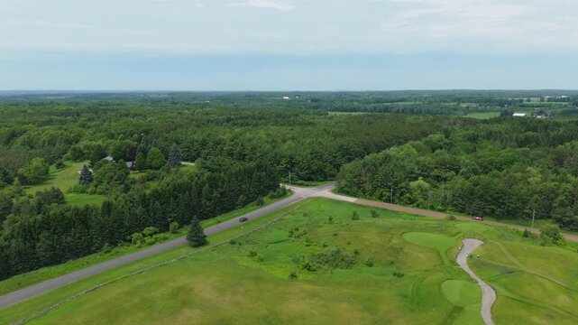 Stunning drone footage glides over Devil's Paintbrush Golf Course near Toronto, showcasing manicured greens, winding paths, and dense forest under bright natural daylight. Scenic aerial video.