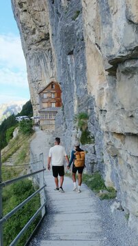 Switzerland offers stunning landscapes as friends stroll along the Aescher Ebenalp trail. A couple marvel at the majestic cliffs and charming mountain huts while enjoying the fresh air.