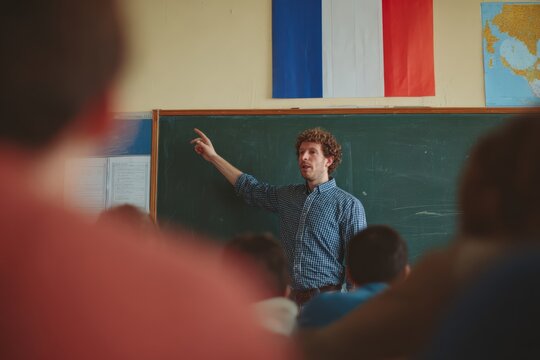 Teacher points at blackboard in classroom with French flag displayed in the background during a language lesson with students present