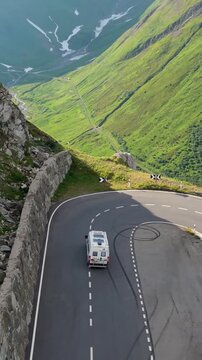 Furkapass Switzerland offers a captivating journey along its winding roads, revealing spectacular mountain views and lush green valleys. A camper van driving on a mountain road in the Swiss Alps