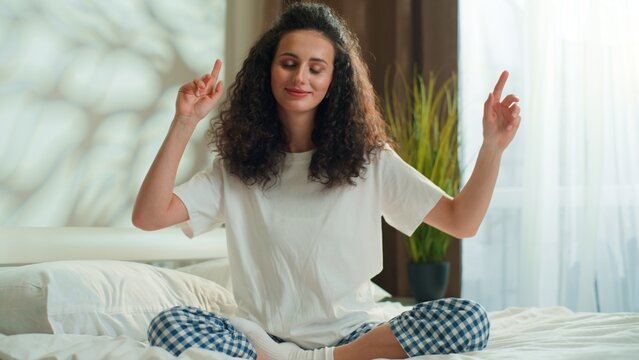 Positive happy Caucasian woman in pajamas singing dancing relaxing on bed at home weekend morning optimistic joyous female girl sing active dance to song music celebrating vacation in hotel in bedroom
