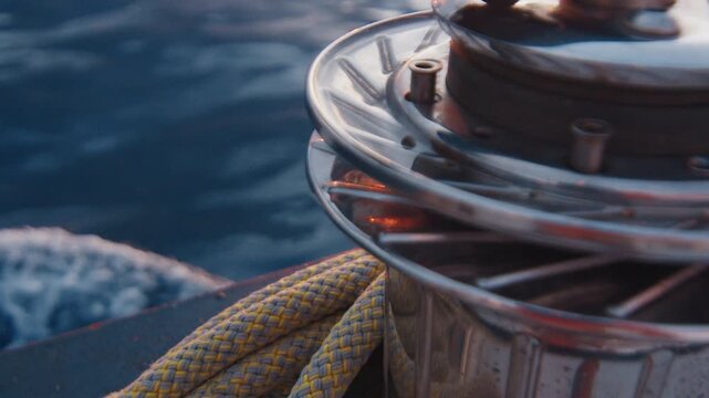 Sailing the Atlantic. Sailing boat moves in the Atlantic Ocean, details of the vessel. Sunset as seen from the moving sailing boat with winch on the foreground