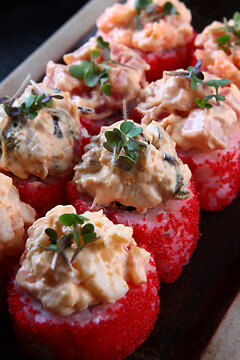 Traditional Japanese cuisine. Spicy rolls with assorted mussels, shrimp, and salmon. White ginger and wasabi. Rolls are garnished with microgreens. Close-up