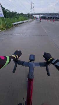 First-person point of view of a road cyclist riding along an urban roadway with light traffic, motorcycles, and an overpass ahead. The immersive footage captures city commuting, active transportation,