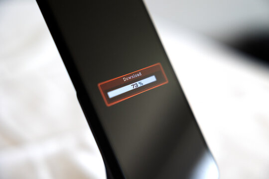 Smart phone screen shows download progress bar, downloading data, software or information. Wireless technology, internet download, status, mobile device, digital asset management, business.