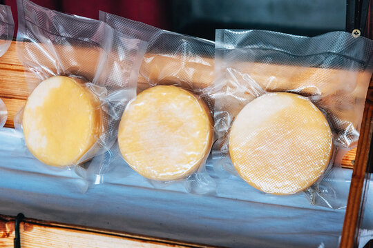 Artisanal cheese wheels vacuum sealed for food preservation and extended freshness, ready for sale at a local market