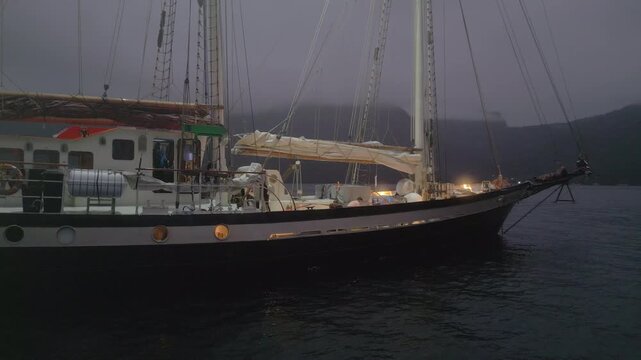 Big expeditional sailing boat anchored in the calm sea at night. Drone night shot