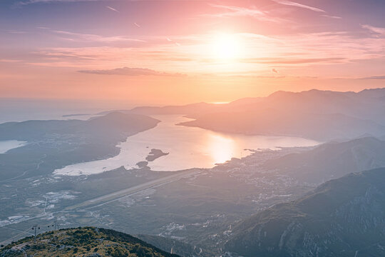 Panoramic view of the serene Bay of Kotor and surrounding mountains, with warm sunset light reflecting on the water