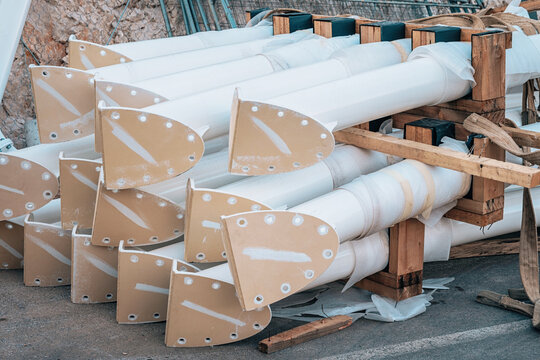 Group of new white industrial pipes with base plates for structural components, wrapped and stacked on a wooden pallet