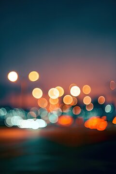 Blurred city lights at dusk glow in a dreamy, abstract street scene