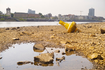 Low stream gauge of rhine river in Düsseldorf,Germany.Water shortage, drought, climate change,global warming concept, dry river bed with skyline of the town of düsseldorf, germany in the background © Thomas Bethge