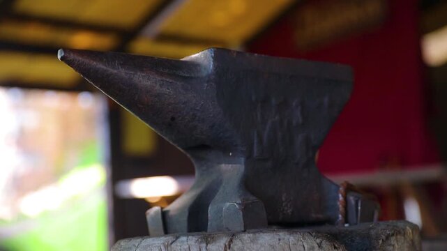 A heavy metal anvil sits atop a wooden block, ready for use in various DIY or crafting projects