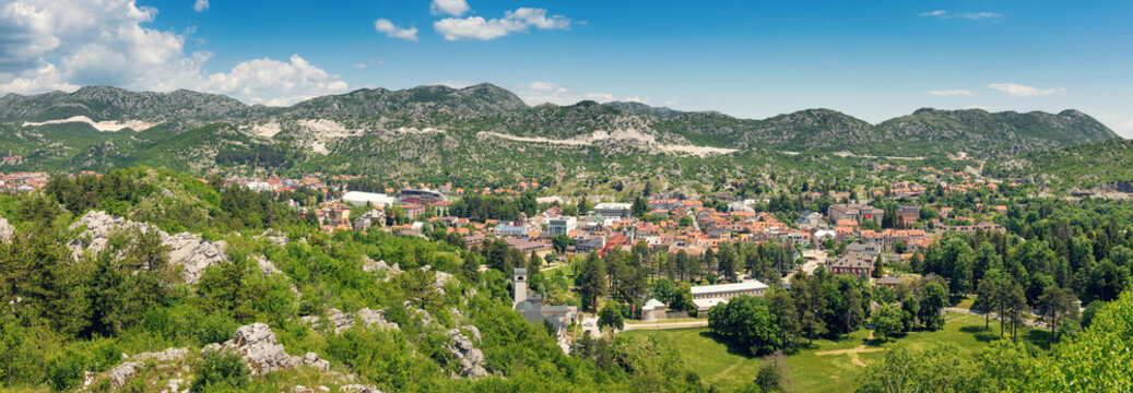 Scenic view of Cetinje, Montenegro, showcasing the town surrounded by green hills, mountains, and a clear blue sky