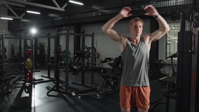 Young man doing jumping jacks in gym. Footage for fitness brand commercials, workout application promos, and healthy lifestyle marketing campaigns