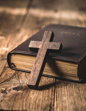 Wooden cross resting on a closed aged Bible on rustic wooden table, Christian faith and spirituality concept, reverent peaceful atmosphere, warm soft lighting, old book texture. Close-up.