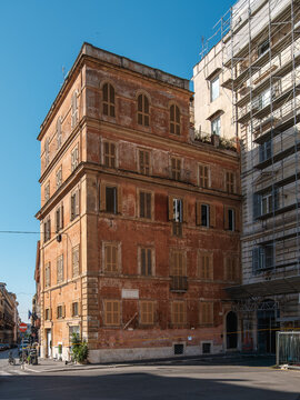 Historic Weathered Terracotta Apartment Building with Traditional Wooden Shutters on a Sunny Street Corner in Rome Italy