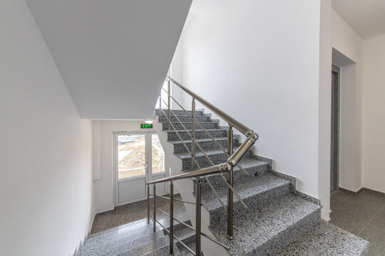 Modern stair case between floors. Stairs with metallic rail in modern building. Interior of a contemporary apartment or office building. Architecture and real estate background.