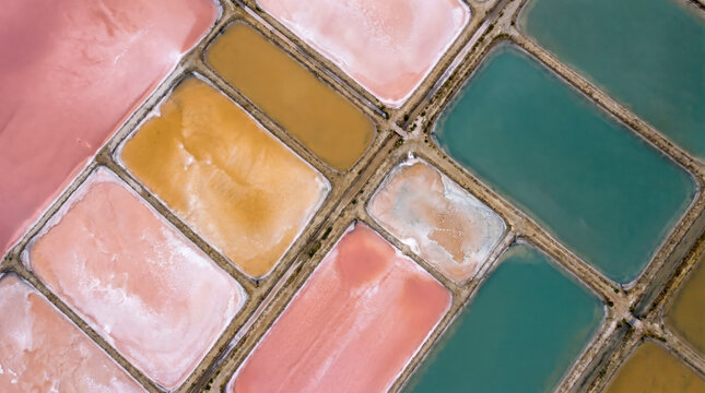 Aerial abstraction of colorful mineral salt ponds forming a vivid checkerboard