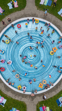 Overhead view of people swimming and floating in a round outdoor public pool