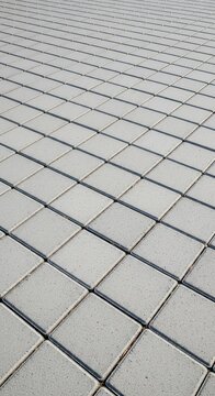 High-angle view of interlocking gray concrete paving stones arranged in a geometric pattern on a suburban walkway or driveway surface, infrastructure, walk, background