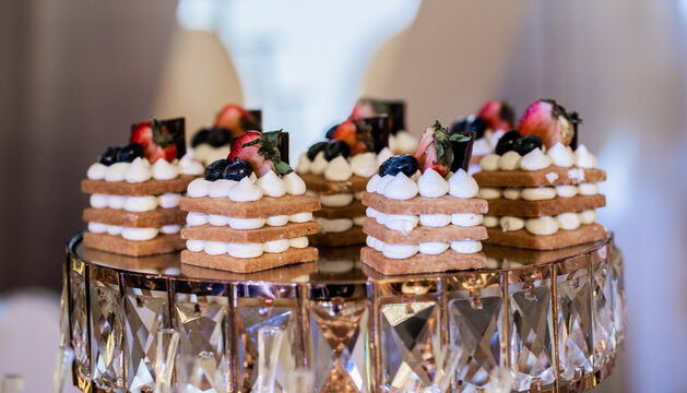 Mini postres gourmet con crema, fresas y ar&aacute;ndanos sobre elegante soporte de cristal para eventos