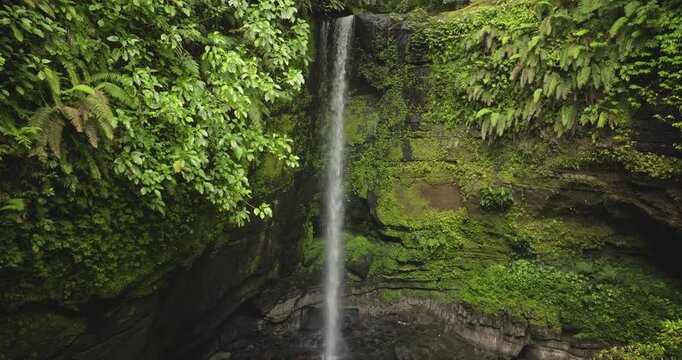 Solomon Islands waterfall cascades into a natural pool, surrounded by vibrant green vegetation and ancient rock formations, highlighting the pristine tropical rainforest ecosystem. Aerial panorama