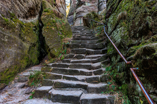 Ancient stone stairway through mossy rocky passage in nature
