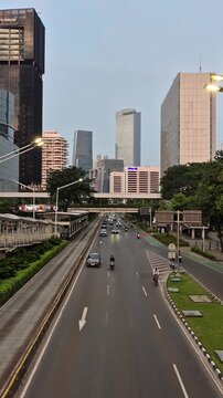 Vertical shot of city traffic and modern skyscrapers along Jenderal Sudirman street in the afternoon in Jakarta, Indonesia