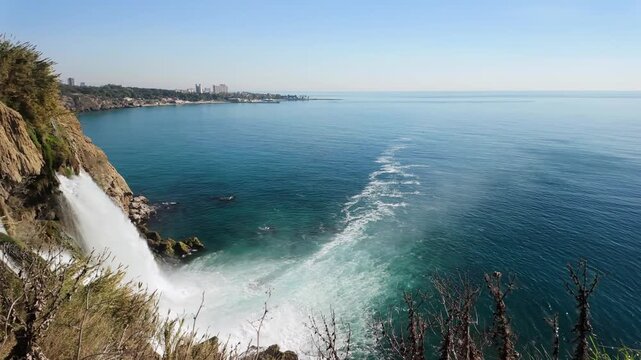 Panning coastal view shows white sea foam meeting calm blue water near duden falls.