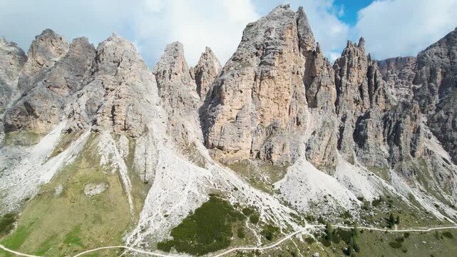 Cinematic Drone Orbit Flight Around Sharp Dolomites Peaks at High Altitude Passo Sella Val Gardena Italy Majestic Alpine Landscape Green Valley Below Epic Mountain Scenery 4K Aerial Footage