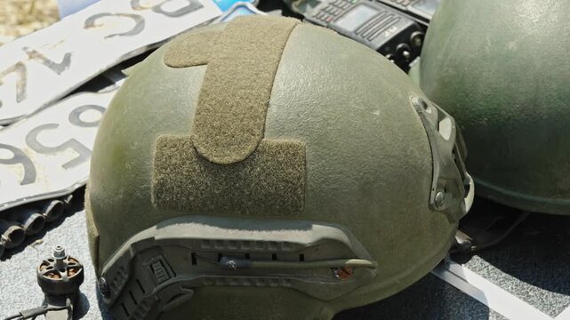 An olive green tactical ballistic helmet with a velcro patch layout, side rails, and NVG shroud.