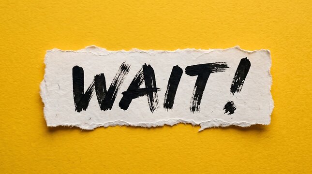 Torn white paper scrap with "WAIT!" in bold black ink on a bright, textured yellow background. Perfect for concepts about patience, pauses, deadlines, or urgent attention.