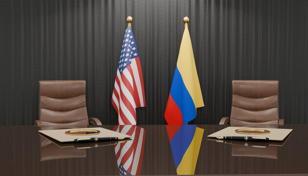 Diplomatic Accord: The flags of the United States of America and Colombia stand side-by-side behind a polished conference table.