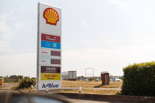 Roadside Shell petrol station price sign displaying fuel prices, Costa Express branding, and Co-op partnership on a clear sunny day in a rural location